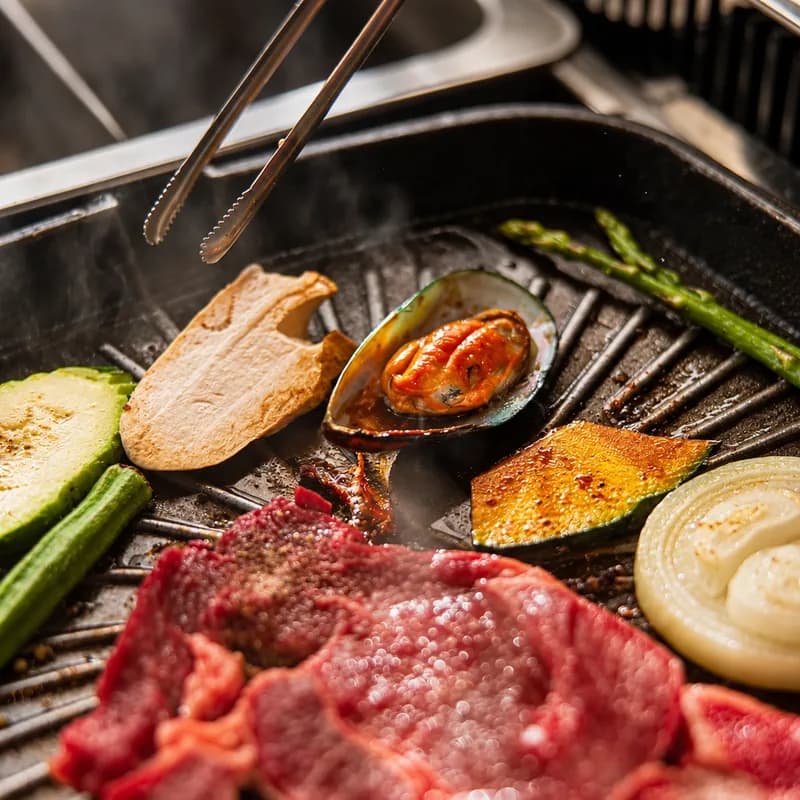 Beef, shrimp and vegetables cooking on a tabletop grill at Sōke