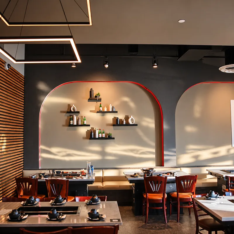 Dining room at Sōke with shelves of sake bottles, pendant lights and grill tables