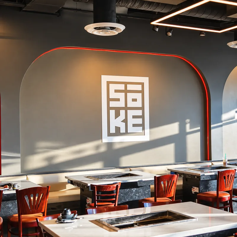 The Sōke dining room with built-in grill tables, red chairs and the Sōke logo on a curved wall