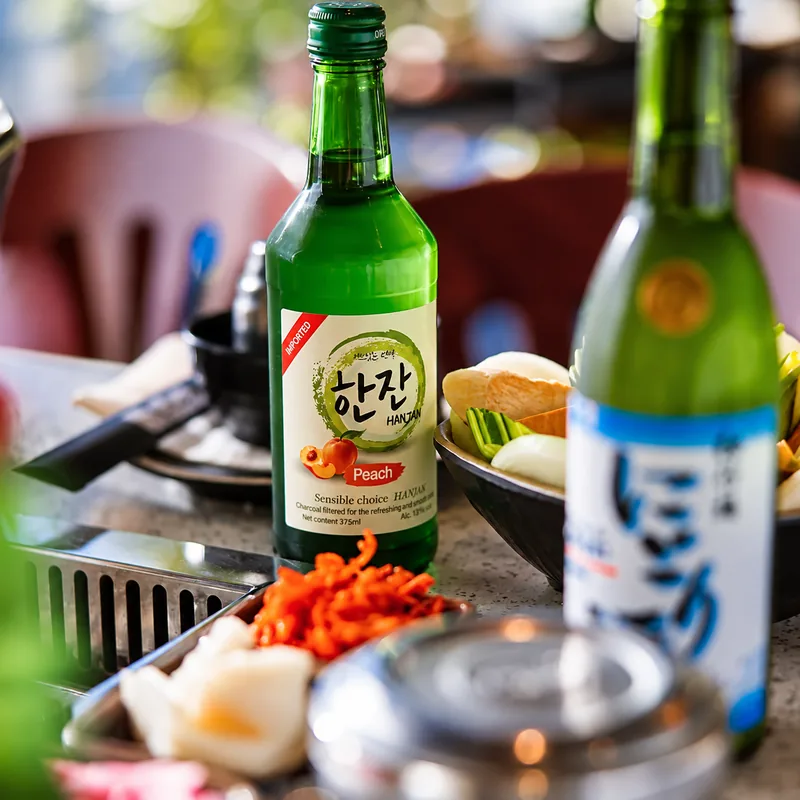 Jinro soju and a bottle of nigori sake on a table at Sōke
